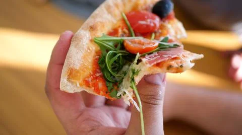 Close up view of a slice of pizza in a human han Stock Photos