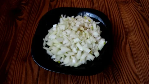 Close-up view sliced onion rotates in a black plate. Cooking concept. Stock Footage 197512096
