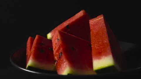 Close up view of sliced watermelon triangles in front of black studio Stock Footage 316578633