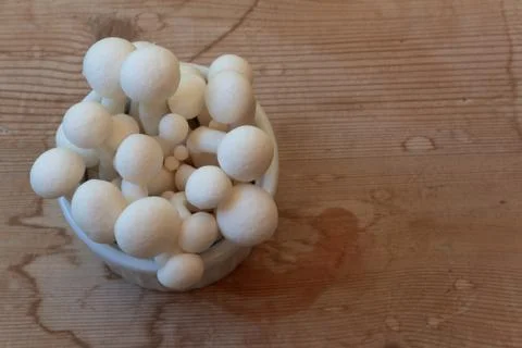 Close view of small dish of white mushrooms on a weathered wood tabletop Stock Photos
