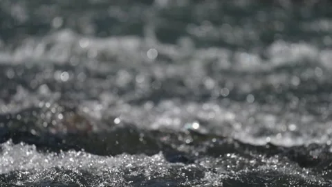 Close-up view of a small river with rushing churning water reflecting the sun Stock Footage 316152937