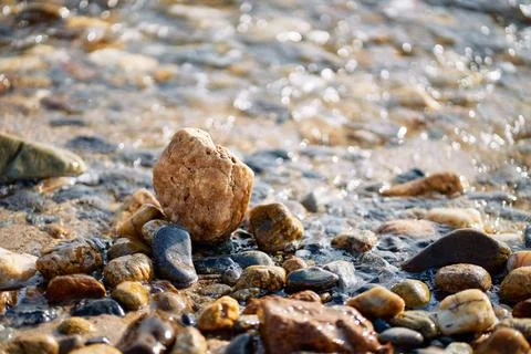 Close-up view of small smooth pebbles and wet sand on a sea shore Stock Photos