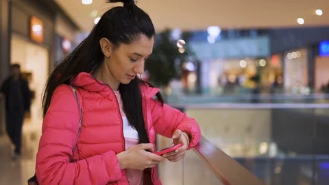 Close view of smiling girl using phone waiting in the mall Stock Footage 125328113