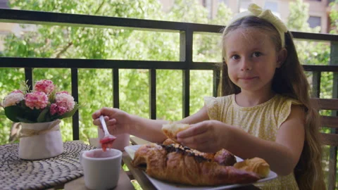 Close-up view of a smiling, happy kid eating baked pastry outdoors Stock Footage 231950046