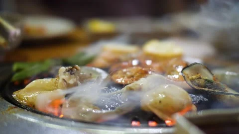Close up view of smoking and sizzling seafoods being cooked on the grill stove. Stock Footage 148245841