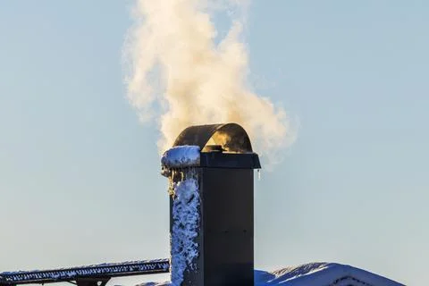 Close up view of smoking chimney covered with snow against background Fotos de archivo