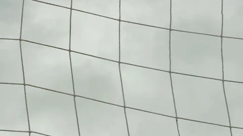 Close up view of a soccer net hanging from a crossbar against an overcast sky Stock Footage 336092436