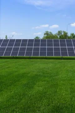 Close up view of solar panel with green grass lawn and blue sky Stock Photos