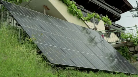 Close-up view of solar panels installed on a house with greenery flowers around Stock Footage 281536089