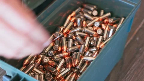 Close up view of someone opening up a can of 9mm ammunition, pulling out a Stock Footage 197976525