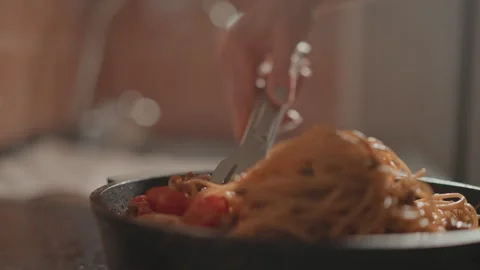 Close view of spaghetti lifted and twirled with metal tongs over shallow pan Stock Footage 346658930