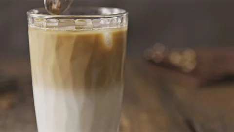 Close up view with spoon is mixing cold coffee cocktail in glass. Stock Footage 129637892