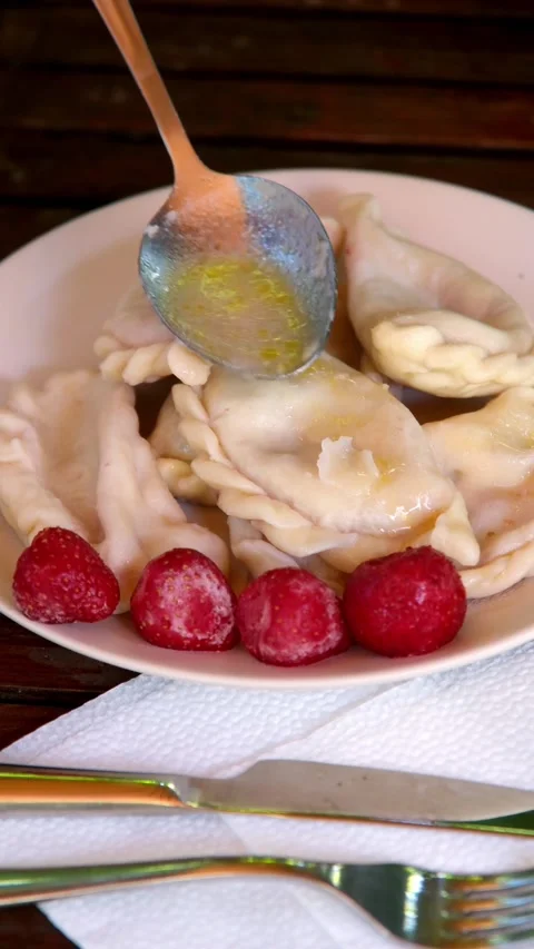 Close up view of spoon pouring melted butter onto boiled dumplings on plate with Stock Footage 345161873