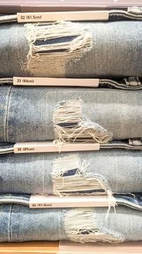 Close-up view. A stack of torn denim jeans on the rack Stock Photos