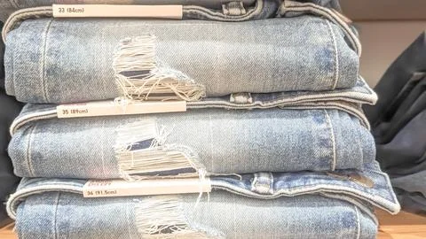 Close-up view. A stack of torn denim jeans on the rack Stock Photos