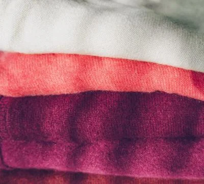 Close up view of stack of white to dark magenta cachemire clothes Stock Photos