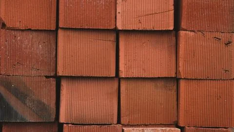 A close up view of stacked red clay bricks highlighting their textured, ridge Stock Photos