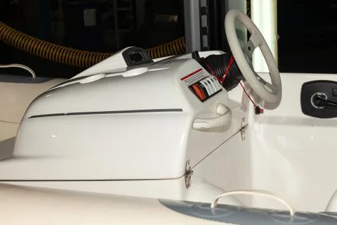 A close-up view of the steering wheel of a small white rubber motorboat with  Stock Photos