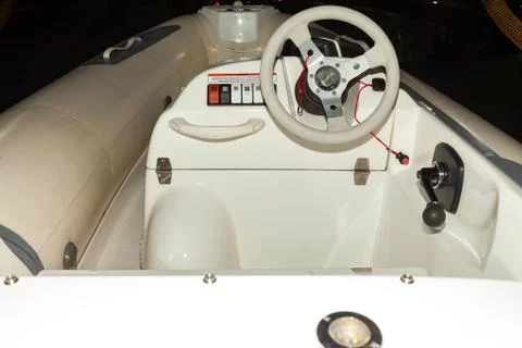 A close-up view of the steering wheel of a small white rubber motorboat with  Stock Photos