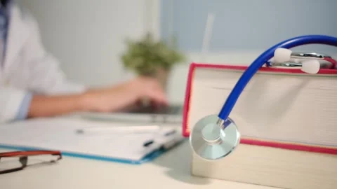 Close up view of stethoscope with books on table and female doctor Stock Footage 251941635