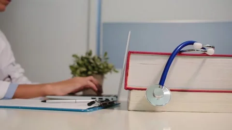 Close up view of stethoscope with books on table and female doctor Stock Footage 251941644