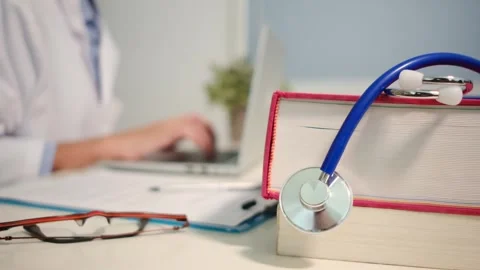 Close up view of stethoscope with books on table and female doctor Stock Footage 251941659