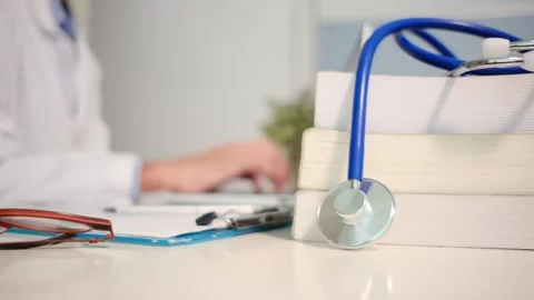 Close up view of stethoscope with books on table and female doctor Stock Footage 251941704