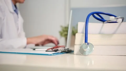 Close up view of stethoscope with books on table and female doctor Stock Footage 251941710