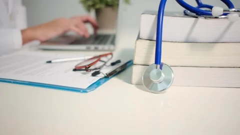 Close up view of stethoscope with books on table and female doctor Stock Footage 251941720