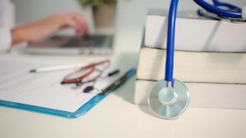 Close up view of stethoscope with books on table and female doctor Stock Footage 251941722
