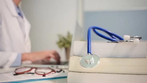 Close up view of stethoscope with books on table and female doctor Stock Footage 251941734