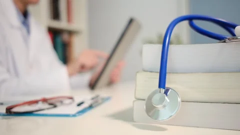 Close up view of stethoscope with books on table and female doctor Stock Footage 251941798