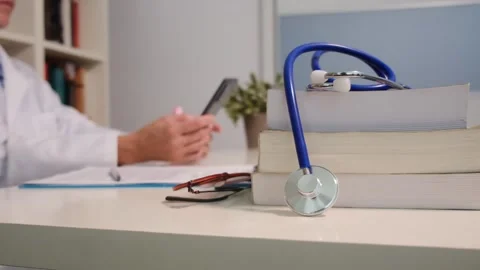 Close up view of stethoscope with books on table and female doctor Stock Footage 251942031