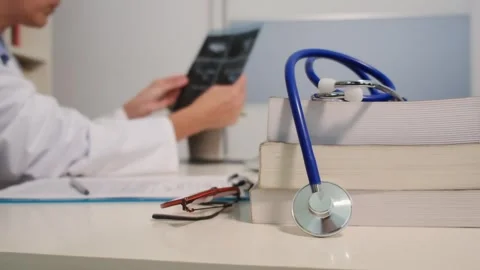 Close up view of stethoscope with books on table and female doctor Stock Footage 251942073