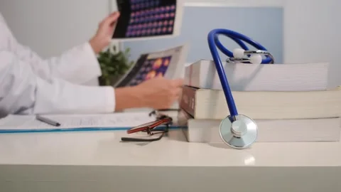 Close up view of stethoscope with books on table and female doctor Stock Footage 251942092
