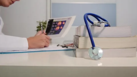 Close up view of stethoscope with books on table and female doctor Stock Footage 251942128