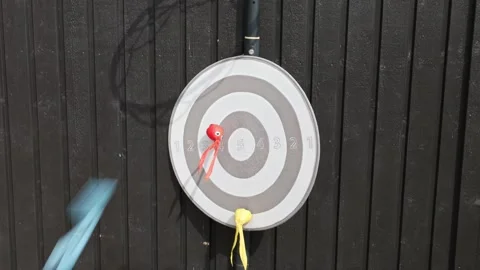 Close-up view of sticky darts flying toward hanging children's target outdoors. Stock Footage 342346485