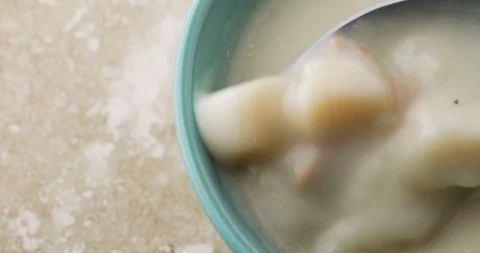 Close view of stirring canned clam chowder with a spoon in a bowl Stock Footage 101998424