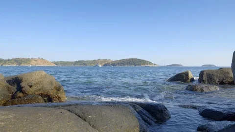 Close up view of stone and waves on rocky beach with many yachts Stock Footage 114985707
