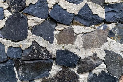 Close view of a stone wall with different shapes and colors of rock pieces .. Stock-Fotos