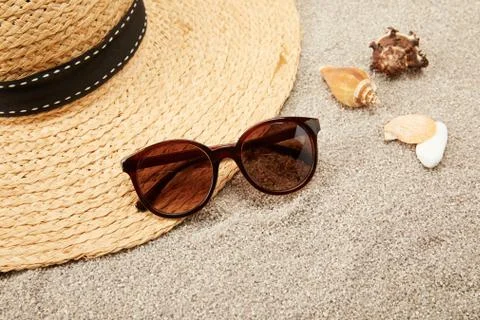 Close up view of straw hat, seashells and sunglasses on sand Stock-Fotos