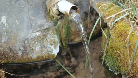 Close-up view of a stream of water emerging from a small pipe sticking down Stock Footage 132021641