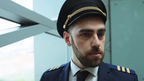 Close up view of strict blue-eyed bearded man in pilot uniform in the hall of Stock Footage 109284524