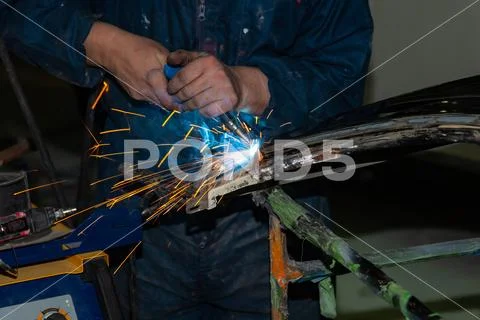 Close-up view strong man is a welder in blue working overalls without gloves Stock Photos