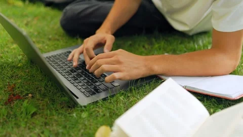 Close up view of student hands typing on a laptop keyboard outdoors. 動画素材 345968578