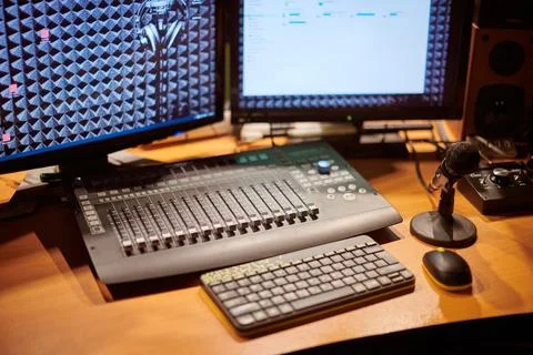 Close up view of studio mixing console, computer screens, and microphone setu Stock Photos