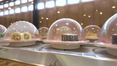 A close-up view of sushi plates moving along a conveyor belt. 库存影片 335003887