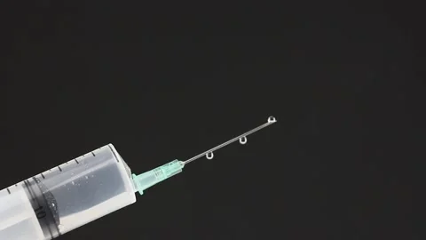 Close-up view on syringe with needle, transparent liquid drops down from needle Video stock 160053515