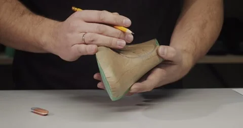 Close up view of tailor draws a sketch on a shoe blank with pencil in private Stock Footage 200127898