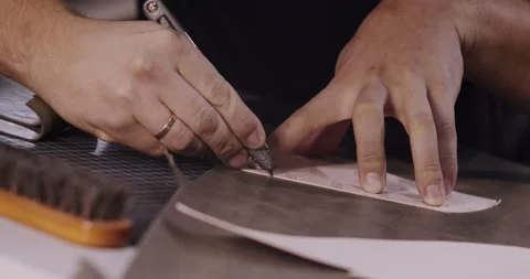 Close up view of tailor hands with knife passing around pattern on leather piece Stock Footage 200127018